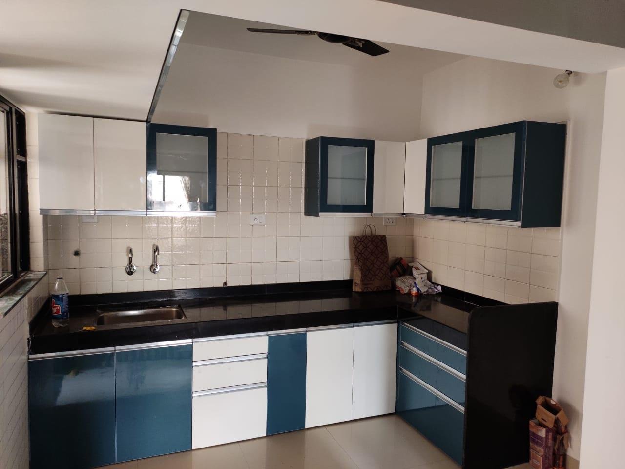 L-shaped modular kitchen in blue and white gloss with a black countertop