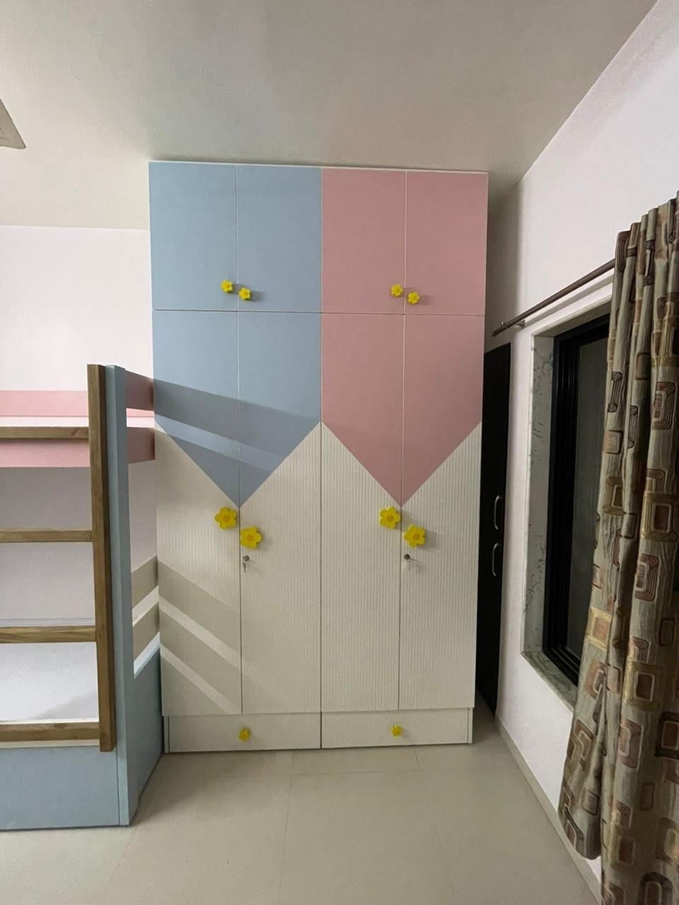 Children's wardrobe in pastel blue and pink laminate with yellow flower knobs
