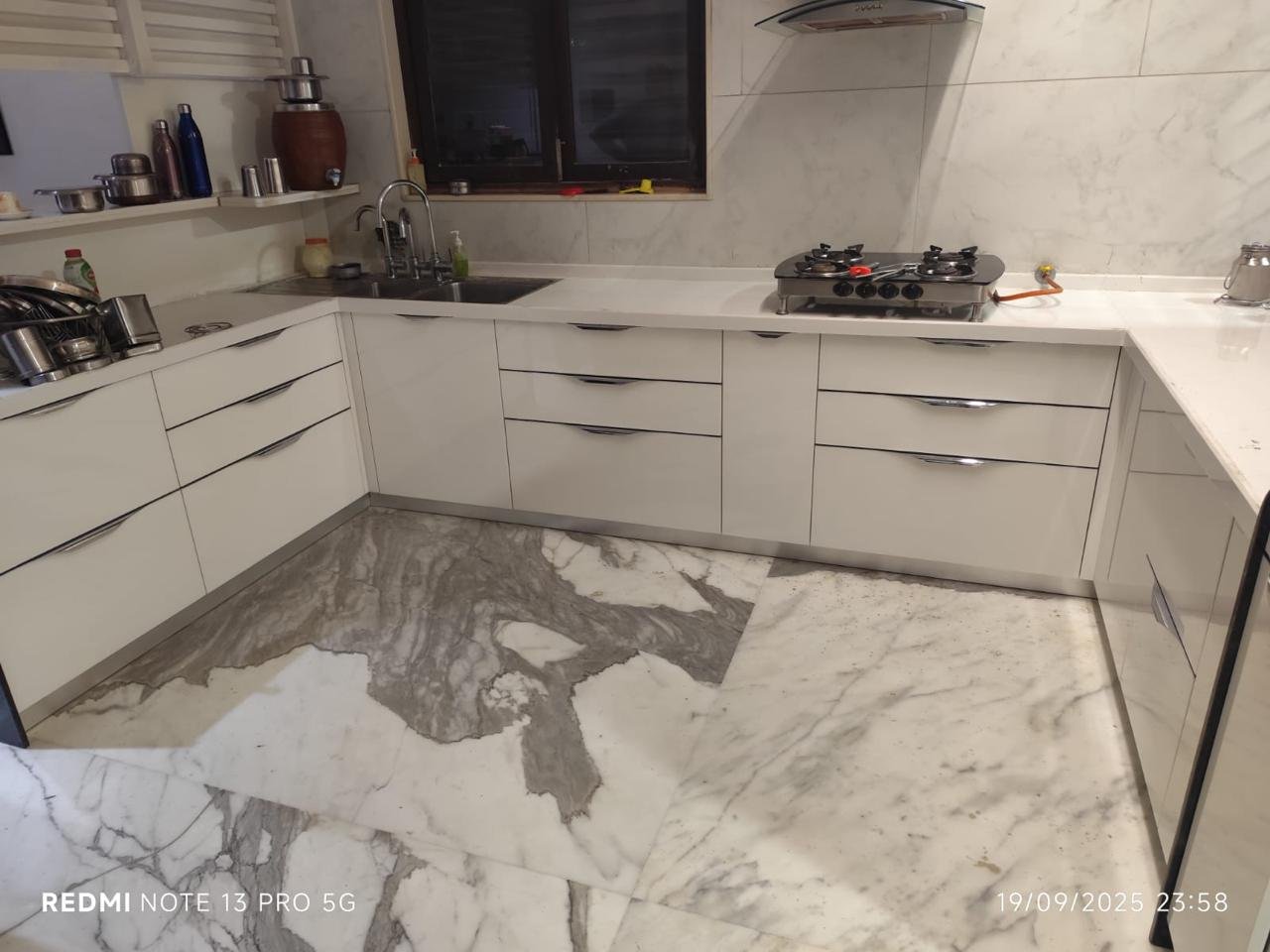 L-shaped modular kitchen in white with slim curved handles