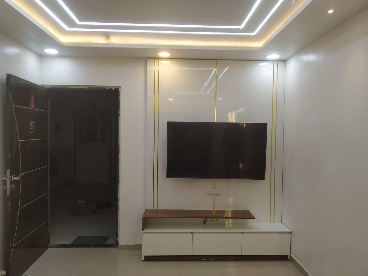 Glossy white TV wall panel with gold inlays and a low media console