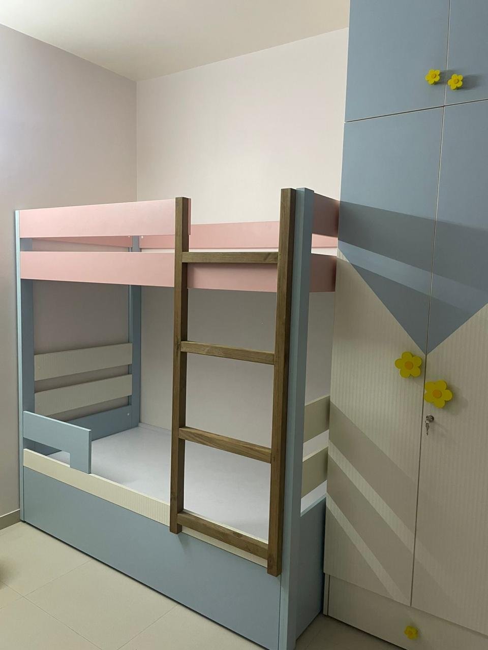 Children's pastel bunk bed beside a flower-knob wardrobe
