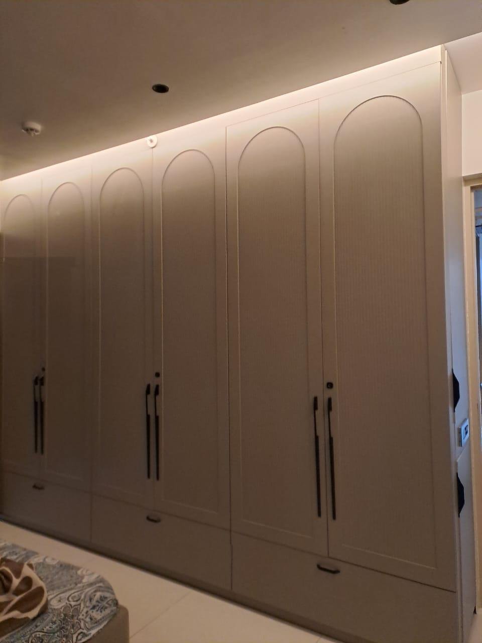 Floor-to-ceiling wardrobe with arched door detailing and soft cove lighting